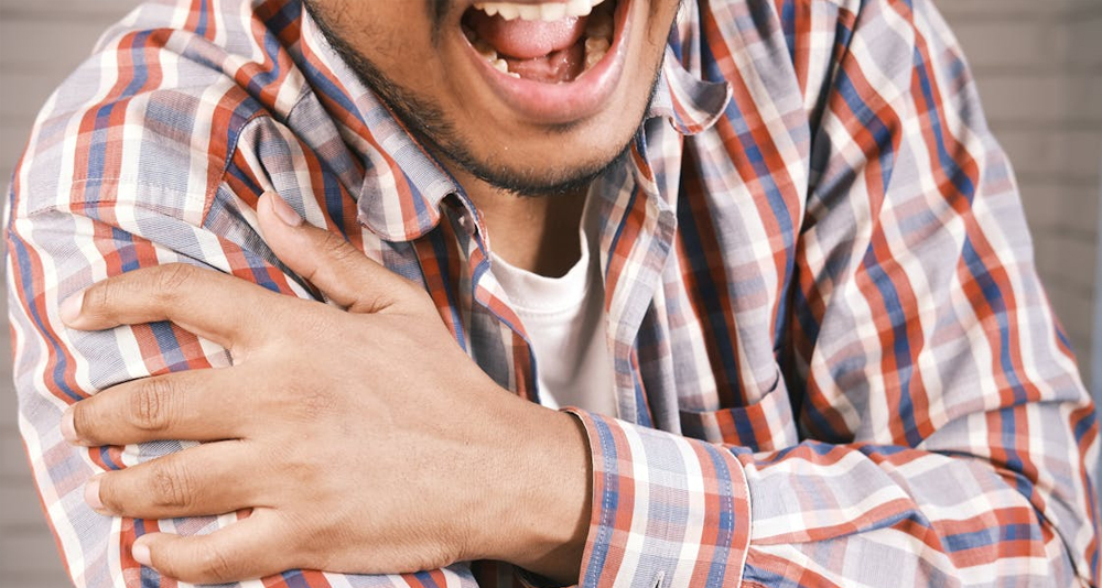 Man holding arm in pain, indicating symptoms of a broken arm