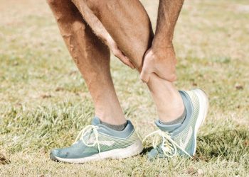 Man holding his lower leg in pain on a grassy field