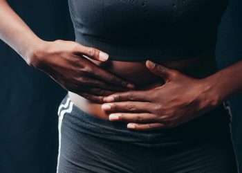 Person clutching pelvic area in pain wearing black athletic wear