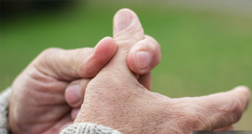 Elderly person holding thumb in pain, indicating possible fracture