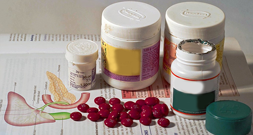 Various medicine bottles and tablets placed on an open medical textbook displaying a diagram of the urinary tract.