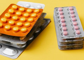 Blister packs of different coloured tablets on a yellow background, representing treatment and home care for skin blisters.
