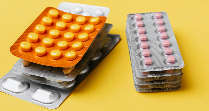Blister packs of different coloured tablets on a yellow background, representing treatment and home care for skin blisters.