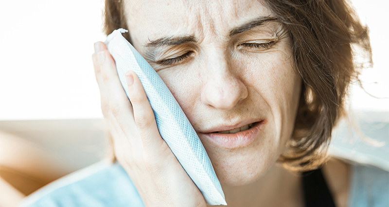 Woman applying a cold compress to her cheek to reduce swelling and pain from a black eye.