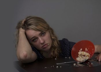Young woman looking distressed after eating, symbolising emotional struggle and the need for treatment of binge eating disorder.