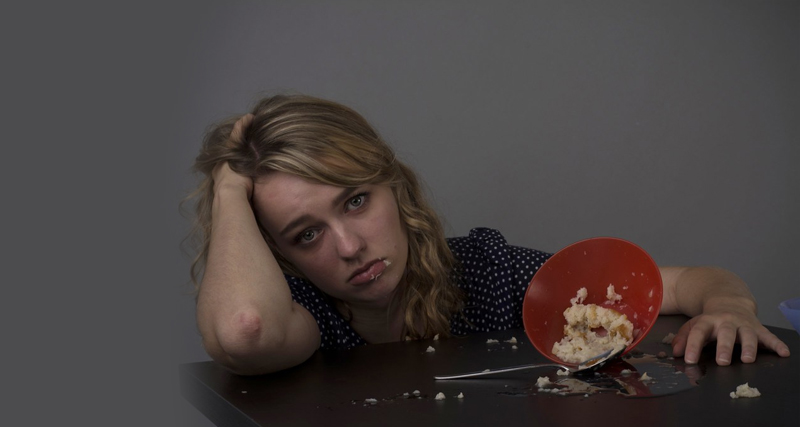 Young woman looking distressed after eating, symbolising emotional struggle and the need for treatment of binge eating disorder.