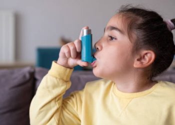 Young girl using an asthma inhaler for bronchitis treatment