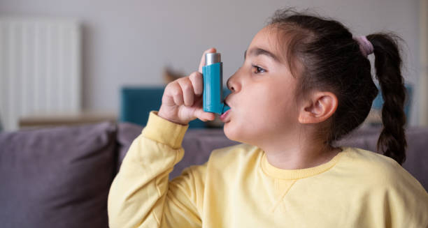 Young girl using an asthma inhaler for bronchitis treatment