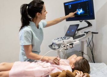 Healthcare professional performing an ultrasound on a young girl to monitor cardiomyopathy