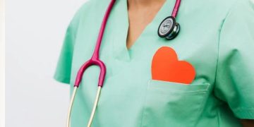 Healthcare worker in scrubs with a stethoscope and red heart shape in pocket