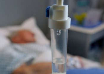 IV drip in focus with patient lying in hospital bed for treatment of cavernous sinus thrombosis