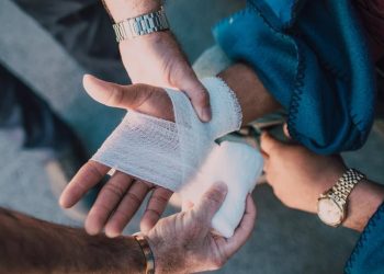 Medical professional wrapping a bandage around a patient's broken wrist