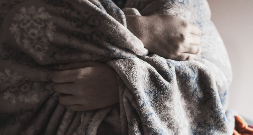 Person wrapped in a blanket seeking comfort during a panic attack