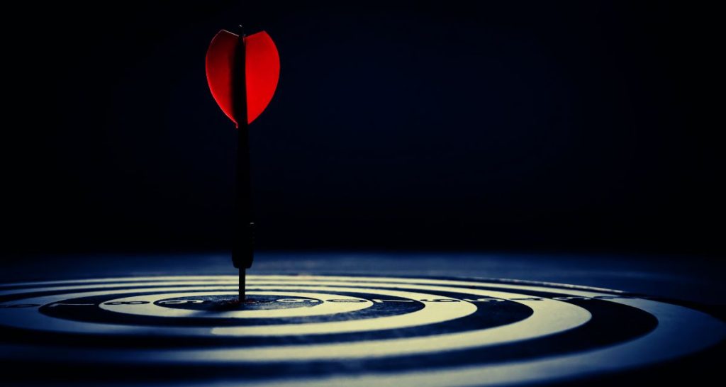 Red dart hitting the bullseye in a dark room symbolising emotional precision