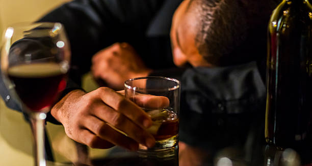Man holding a glass of alcohol with his head down, illustrating alcohol as a cause of chronic pancreatitis.