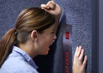 Woman panicking inside lift highlighting causes of claustrophobia