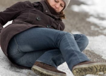 Woman falling on icy ground, holding her lower back