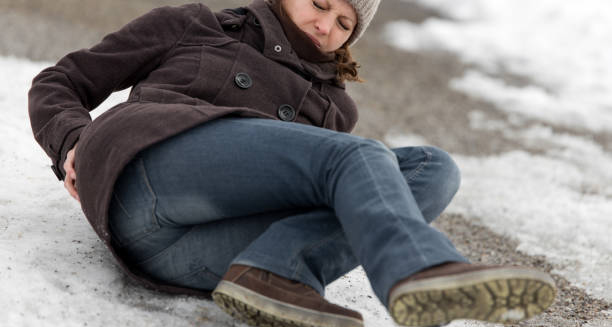 Woman falling on icy ground, holding her lower back