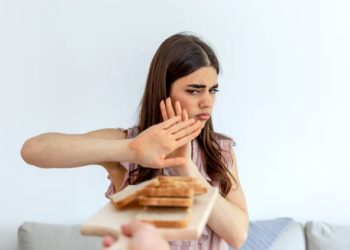 Woman rejecting a plate of bread due to gluten intolerance