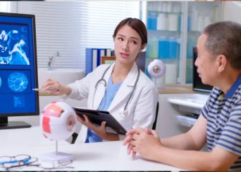 Eye specialist explaining digital retinal scans to an older male patient