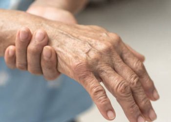 Elderly person holding their hand in pain due to nerve-related discomfort