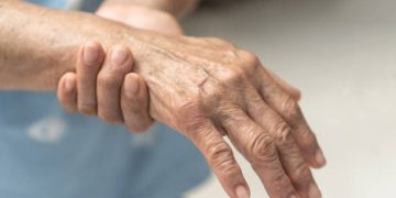Elderly person holding their hand in pain due to nerve-related discomfort