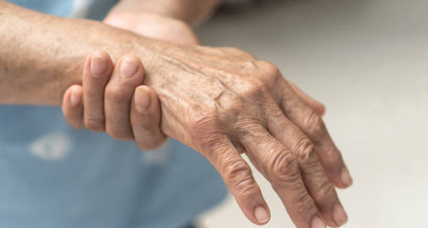 Elderly person holding their hand in pain due to nerve-related discomfort