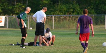 Football player receiving medical attention after head injury, a common cause of concussion
