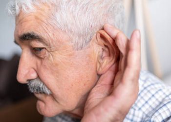 Elderly man cupping his ear to hear better, indicating hearing los