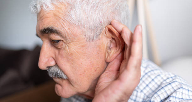 Elderly man cupping his ear to hear better, indicating hearing los
