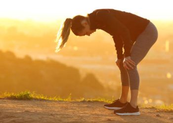 Woman bent over and fatigued after exercise in the sun