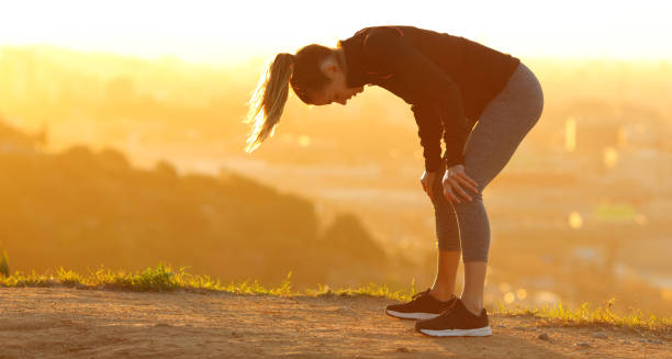 Woman bent over and fatigued after exercise in the sun