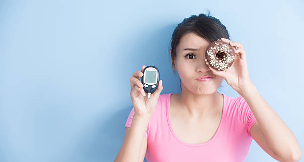 Woman holding glucose meter and donut, symbolising causes of diabetic retinopathy