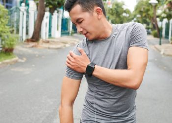 Man clutching his shoulder in pain after possible injury during outdoor activity