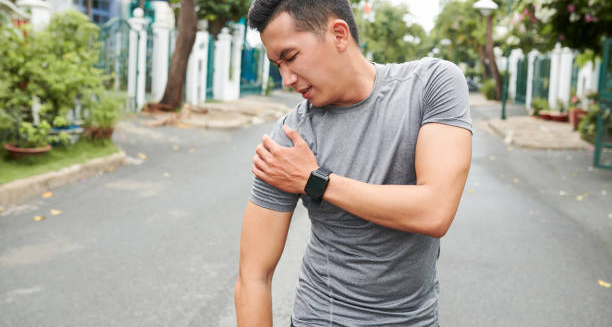 Man clutching his shoulder in pain after possible injury during outdoor activity
