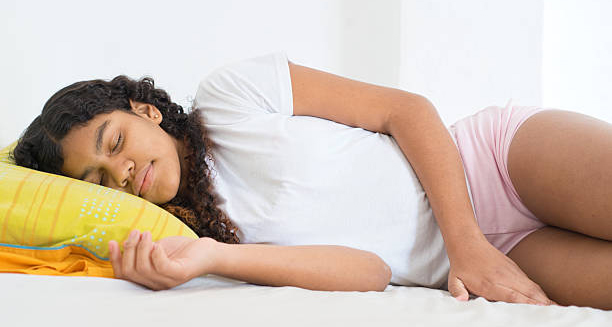 Young girl lying in bed, possibly experiencing early puberty symptoms