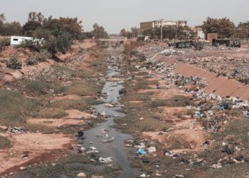 Contaminated waterway surrounded by litter in an urban area contributing to disease spread.
