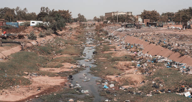 Contaminated waterway surrounded by litter in an urban area contributing to disease spread.
