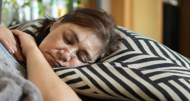 Older woman sleeping on a patterned pillow during the day