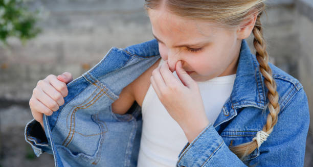 Young girl smelling her underarm for body odour