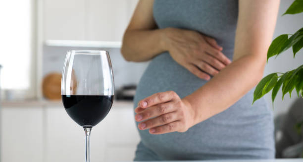 Pregnant woman reaching for a glass of red wine, highlighting the cause of Fetal Alcohol Spectrum Disorder