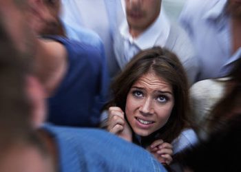 Woman feeling trapped in a crowd, showing signs of claustrophobia