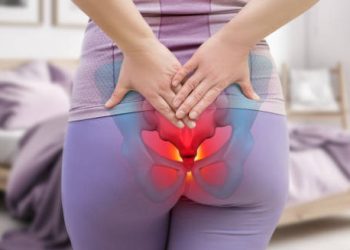 Woman holding lower back with coccyx area highlighted in red