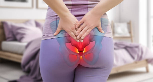 Woman holding lower back with coccyx area highlighted in red