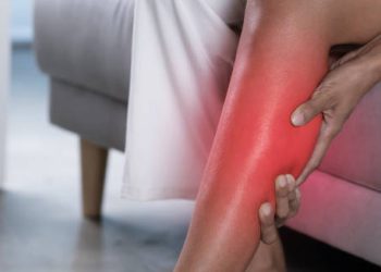 Woman gripping her lower leg in pain with red area indicating inflammation
