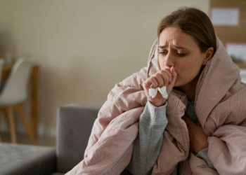 Woman coughing and wrapped in a blanket, showing complications of chronic obstructive pulmonary disease.