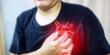 Man clutching chest with a digital heart illustration, representing complications from congenital heart disease