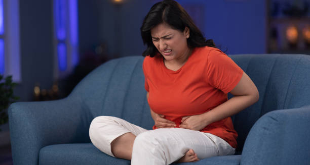 Woman sitting on a sofa with abdominal pain from constipation