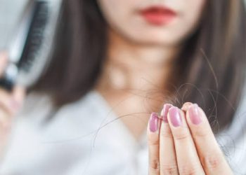 Woman noticing hair fall after brushing, linked to dandruff