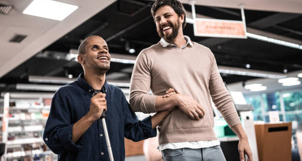 Blind man being guided by a friend in a modern indoor setting